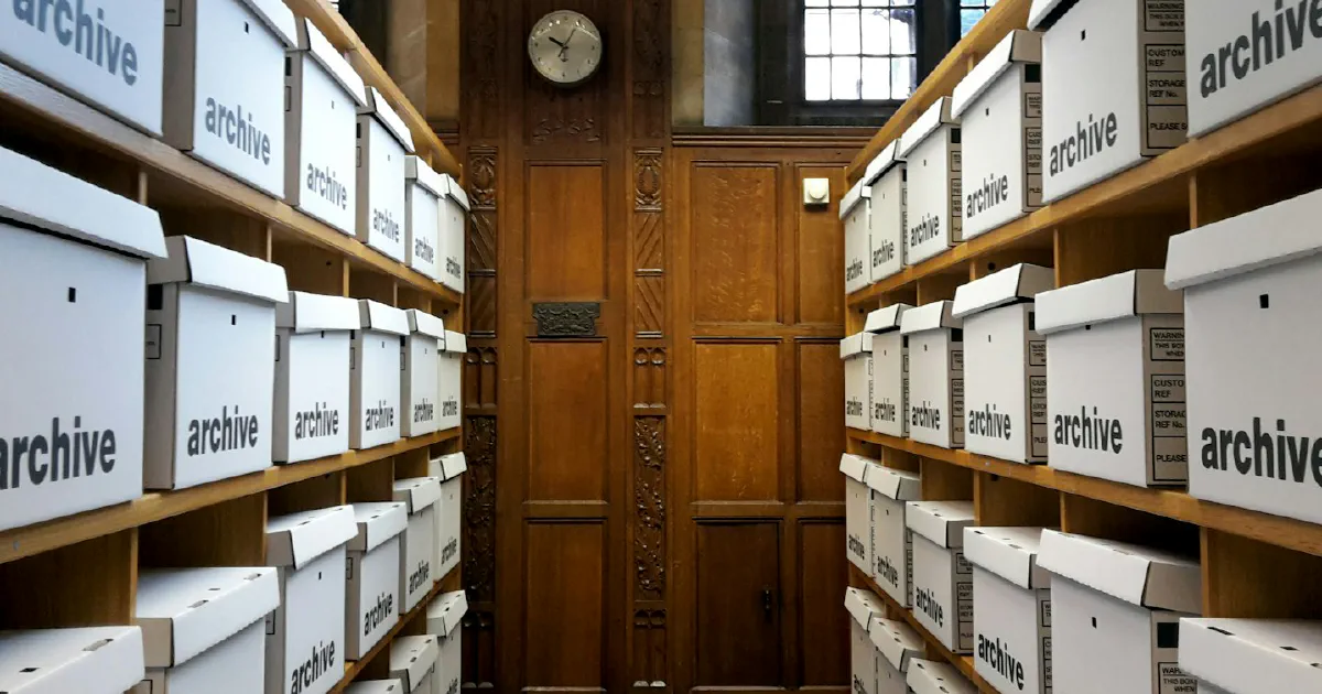 Rows of white archive boxes on wooden shelves