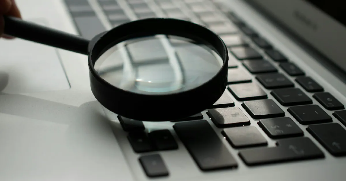 Magnifying glass next to a laptop